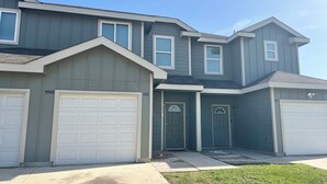 A two-story house with a garage, a front door, and a small porch.