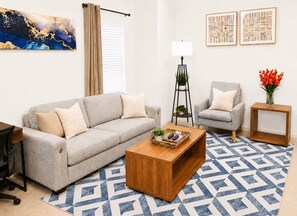 A living room with a sofa, armchair, coffee table, and a patterned rug. - [HB101] New 3BR w/Parking I Family Friendly & Stocked I Near JBSA Randolph AFB (San Antonio)