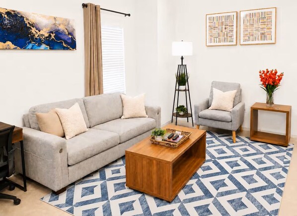 Open-concept living room area with ample seating, smart TV and a workstation