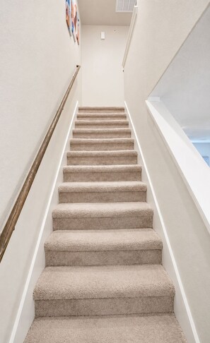A carpeted staircase with a handrail, leading to a landing with a window. - [HB101] New 3BR w/Parking I Family Friendly & Stocked I Near JBSA Randolph AFB (San Antonio)