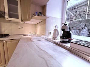 A modern kitchen with white countertops, a built-in oven, and a stone backsplash.