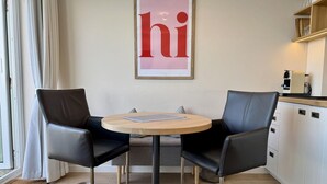 A modern kitchen with a round wooden table and two black leather chairs. - Seeluft - Modern 1-room apartment with balcony and sea view, parking space, WLAN. (Sylt)