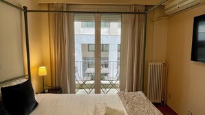 A hotel room with a bed, a bedside lamp, a radiator, and a view of the outside balcony.