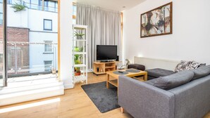 A modern living room with a grey sofa, a TV, and a bookshelf with plants. - 3 Bed in Dublin city centre 10min to Spire (Dublin 1)