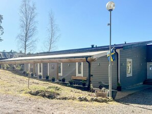 A row of single-story cabins with a covered walkway, outdoor seating, and a flagpole. - 5 Star Holiday Home in Eksjo (Eksjo)