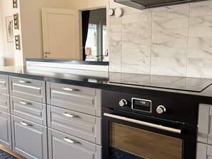A kitchen with a black oven, a digital clock, and a marble backsplash. - 5 Star Holiday Home in Eksjo (Eksjo)