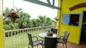 A balcony with a round table and four chairs, surrounded by a white railing. - CHALET JAUNE, a 2300m2 park, wifi, parking, swimming pool, kitchen, happiness (Saint-Pierre)