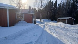 A snow-covered path leading to a wooden building with a garage. - 5 Person Holiday Home in Lidsjoberg (Lidsjöberg)