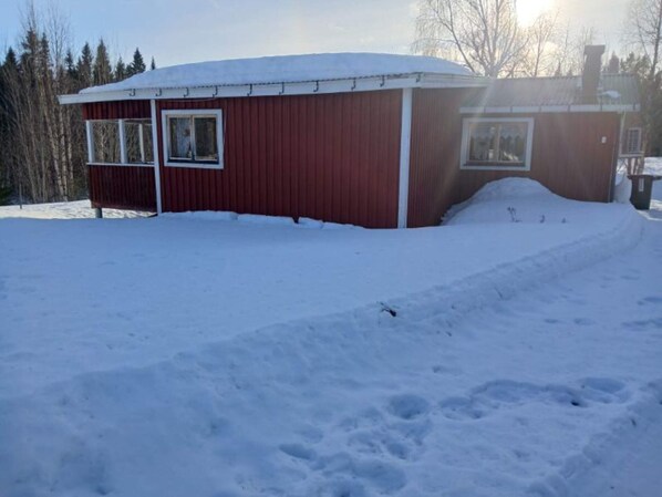 A red building with a snow-covered roof and windows, surrounded by snow. - 5 Person Holiday Home in Lidsjoberg (Lidsjöberg)