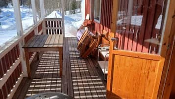 A wooden deck with a grill, a table, and chairs.