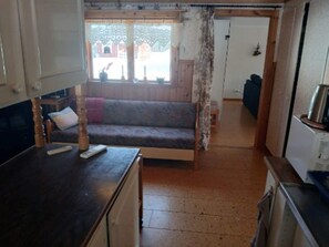 A compact living space with a sofa, a small table, and a kitchenette area. - 5 Person Holiday Home in Lidsjoberg (Lidsjöberg)