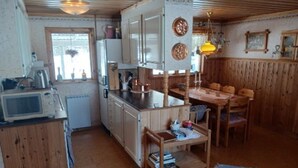 A compact kitchen with wooden cabinets, a microwave, and a dining area with a table and chairs. - 5 Person Holiday Home in Lidsjoberg (Lidsjöberg)