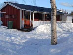 A red building with a porch and a snow-covered ground.