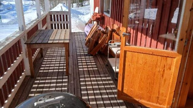 A wooden deck with a grill, a table, and chairs, overlooking a snowy landscape. - 5 Person Holiday Home in Lidsjoberg (Lidsjöberg)