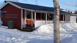 A red building with a white porch and a snow-covered ground. - 5 Person Holiday Home in Lidsjoberg (Lidsjöberg)