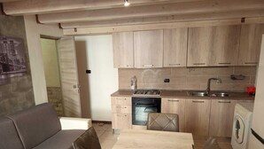 A compact kitchen with wooden cabinets, a dining table, and a sofa. - Little apartment at André's a few minutes from the center of Lecce (Lecce)