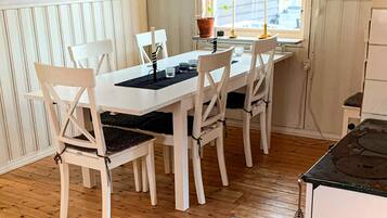 A dining area with a white table and chairs, a window with a view, and a potted plant on the windowsill.