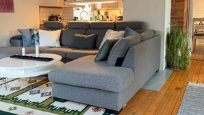 A modern living room with a grey sectional sofa, a white coffee table, and a patterned rug. - 8 Person Holiday Home in Arla (Arla)