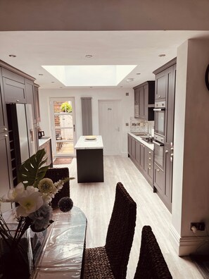 A modern kitchen with a central island, dark cabinetry, and a skylight. - Stylish 5-Bed Home, Off-Street Parking, for families, groups, or business stays (Kidderminster)