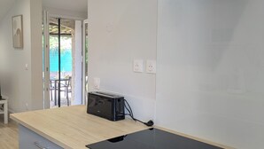 A modern kitchen with a black induction cooktop, a built-in oven, and a white range hood. - Charming House with garden, close to the beach - Aircond & Parking (Palavas-les-Flots)