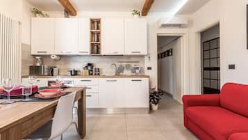 Een moderne keuken met witte kasten, een houten aanrechtblad en een zithoek met een rode bank.