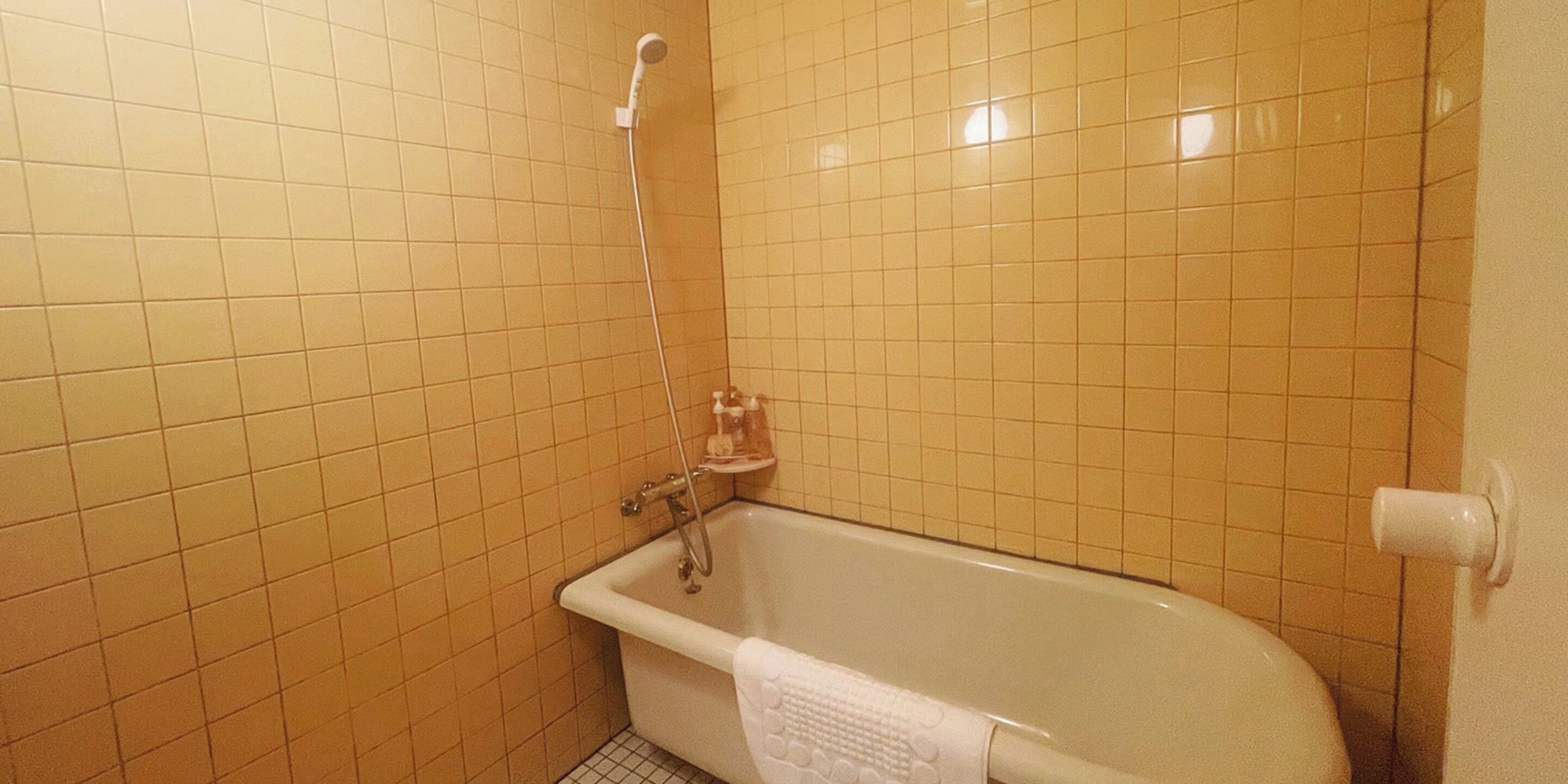 A bathroom with a bathtub, a showerhead, and a towel rack.