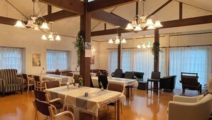 Zona pranzo con tavoli e sedie, travi in legno e lampade a sospensione.