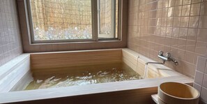 A bathtub with a window above it, a faucet, and a wooden bucket. - Pension Balmy (Nasu)