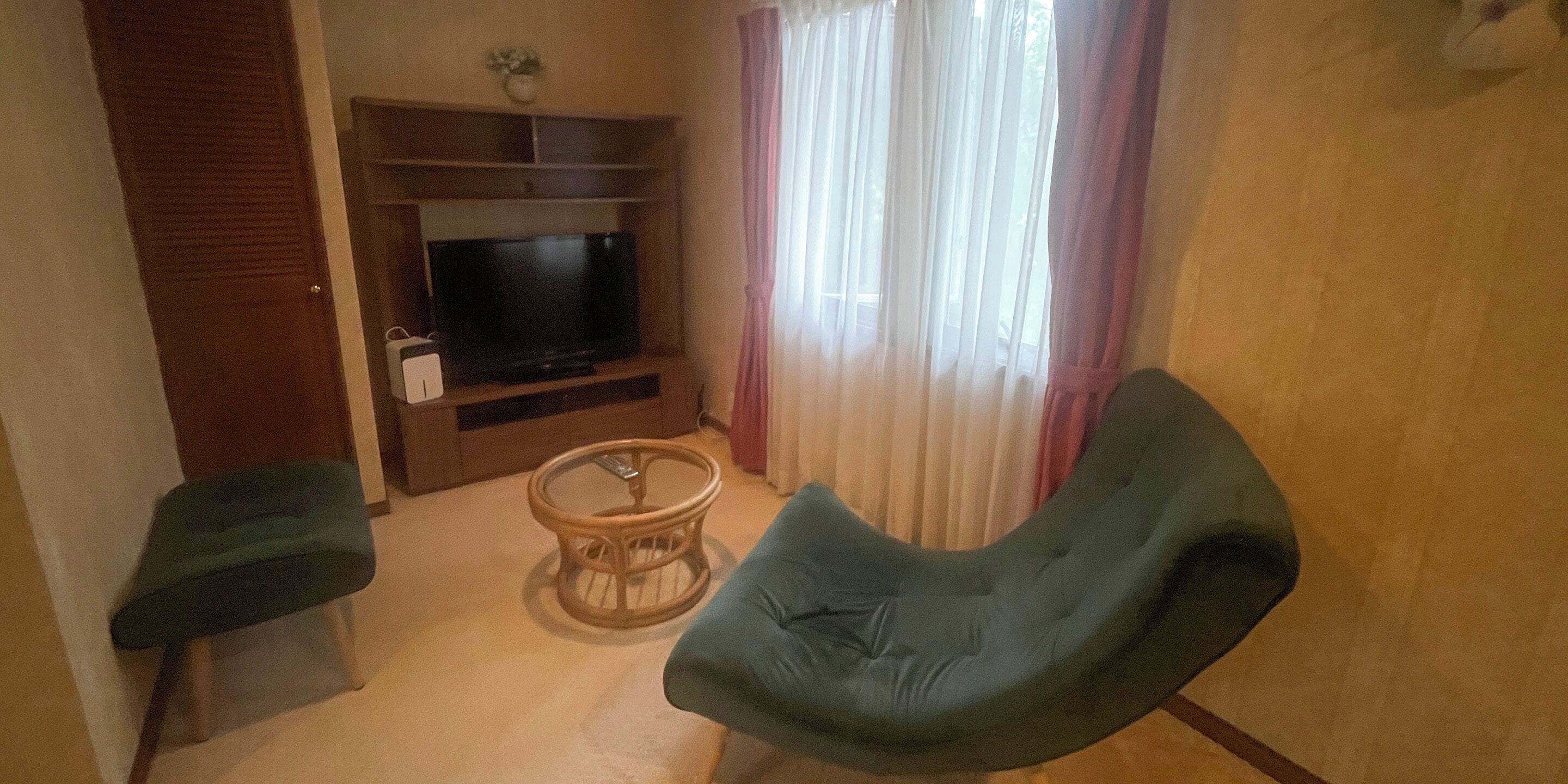 Uma sala de estar com televisão, uma mesa de centro redonda e duas cadeiras.