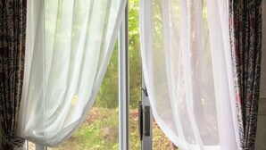 Una finestra con tende trasparenti bianche e drappeggi decorati.