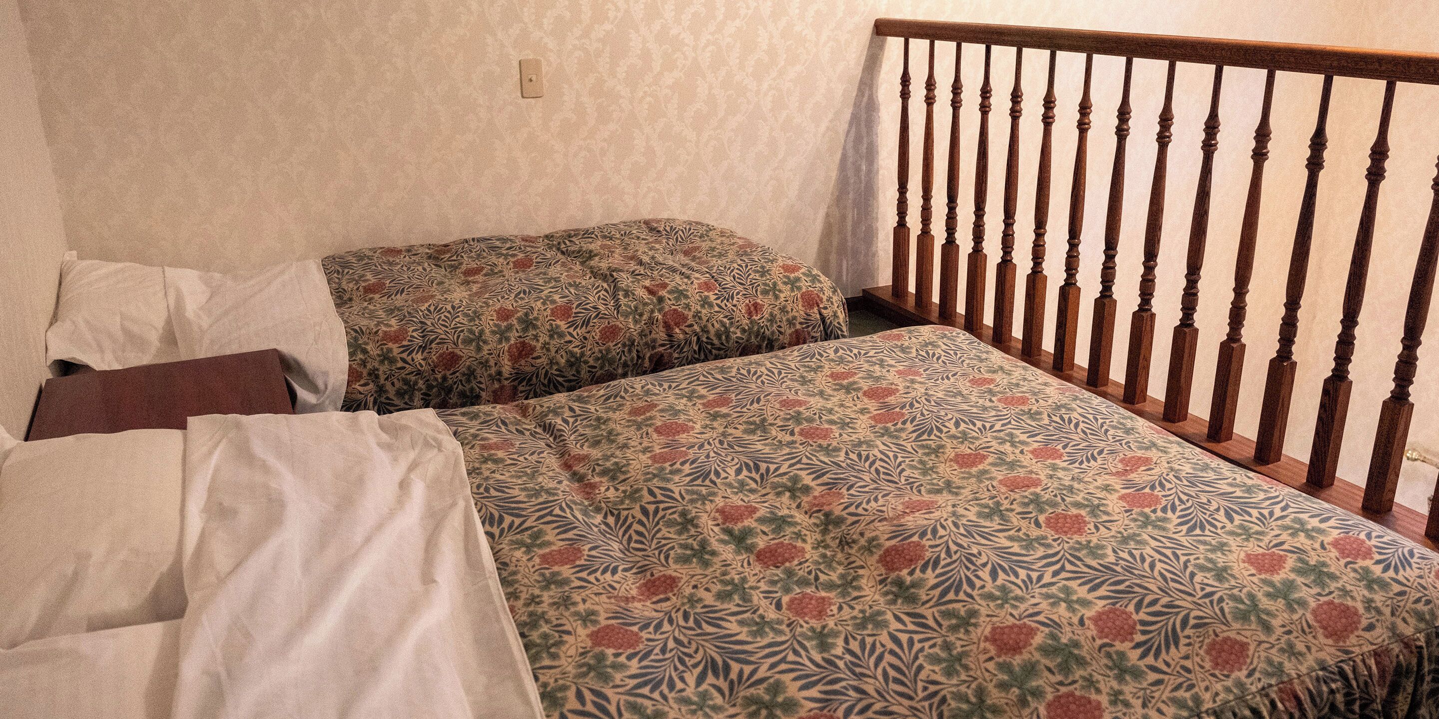 Une chambre avec deux lits, une tête de lit en bois et une literie à motifs.