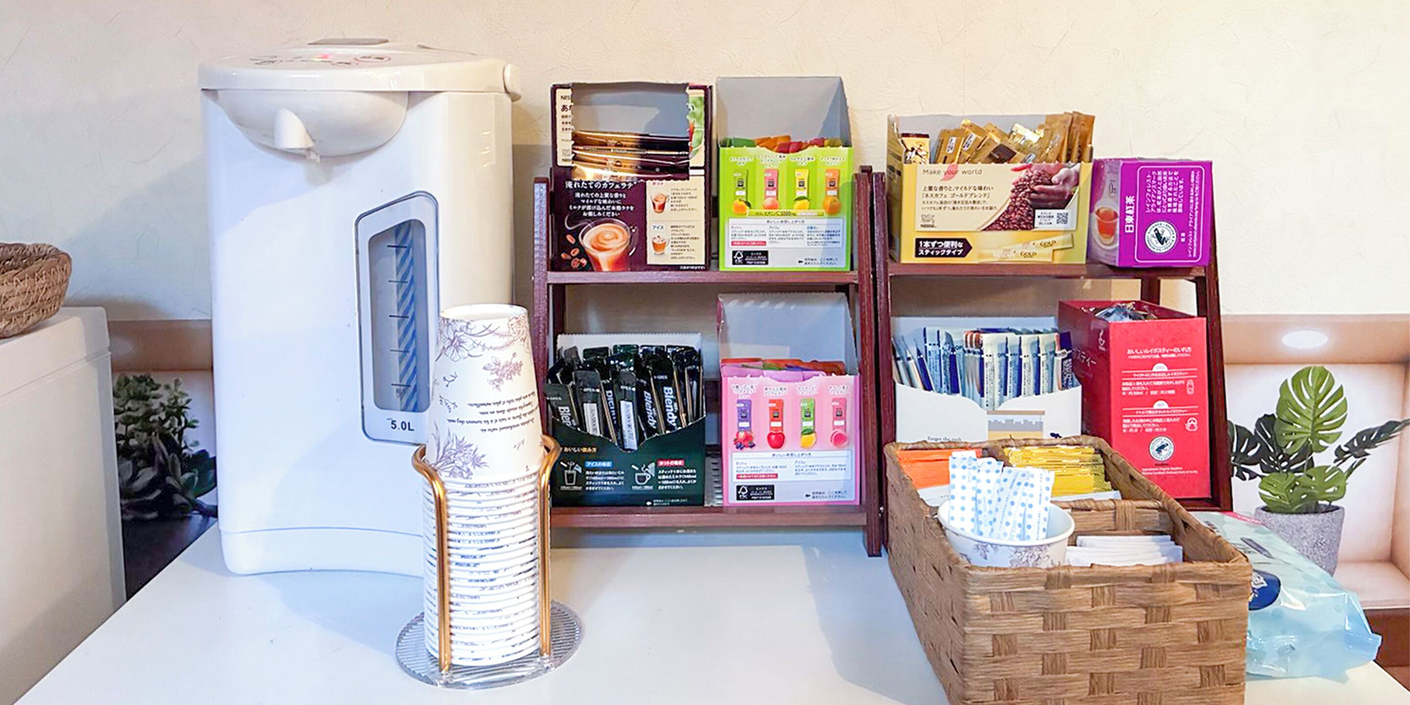 Une machine à café, une pile de rouleaux de papier toilette et des étagères remplies de divers produits emballés.