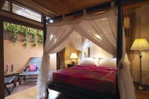 Un lit à baldaquin, une lampe de chevet et une chaise avec un coussin.