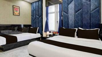 A hotel room with two beds, a marble floor, a painting on the wall, and a window with curtains.