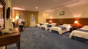 A hotel room with four single beds, a desk, a chair, and a lamp. - Al Naseem Hotel (Makkah)