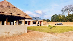 A modern building with a thatched roof and solar panels, surrounded by a well-maintained lawn and a brick wall. - The Ridge Grandstay (Manyama)