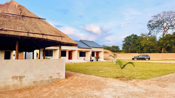 A modern building with a thatched roof and solar panels, surrounded by a well-maintained lawn and a brick wall.