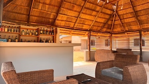 An outdoor bar area with wicker furniture and a thatched roof. - The Ridge Grandstay (Manyama)
