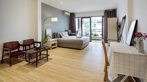 Ein modernes Hotelzimmer mit einem Bett, einem Esstisch, zwei Stühlen, einem kleinen Tisch mit einer Vase und einem großen Fenster mit Blick auf die Stadt.