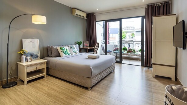 Ein modernes Schlafzimmer mit Bett, Nachttisch, Lampe, Klimaanlage, Kleiderschrank und Fernseher.