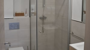 A modern bathroom with a glass-enclosed shower, a toilet, and a sink. - Avio Apartament - Pedrouso View Suite (Santiago de Compostela)