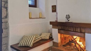 A cozy living room with a fireplace, a clock, and a window.