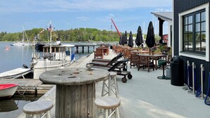 Un restaurante frente al agua con terraza, un muelle con barcos y vistas al lago.