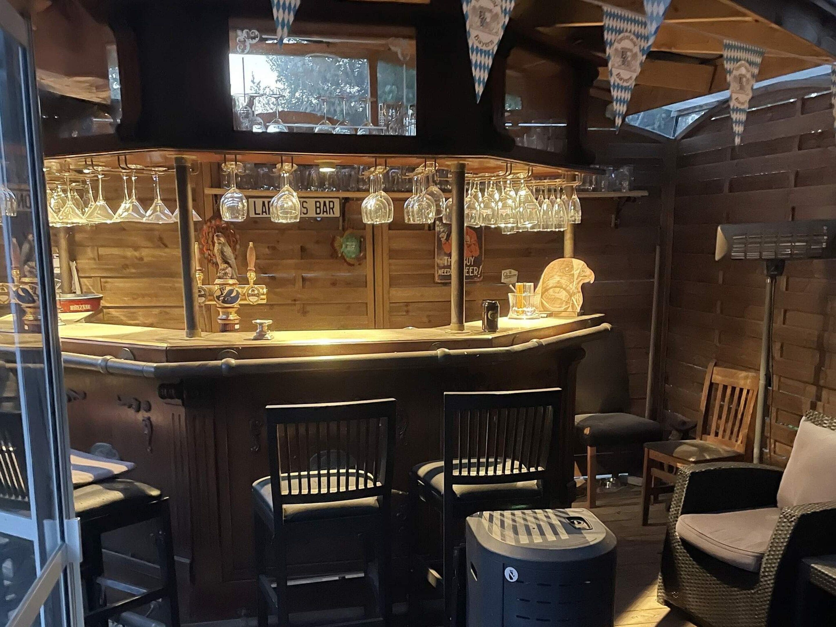 Eine Bar mit Holzwänden, hängenden Gläsern und einem Zapfhahn.