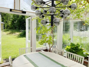 A conservatory with a table and chairs, surrounded by glass walls and a view of greenery. - 5 Star Holiday Home in Graddo (Gräddö)