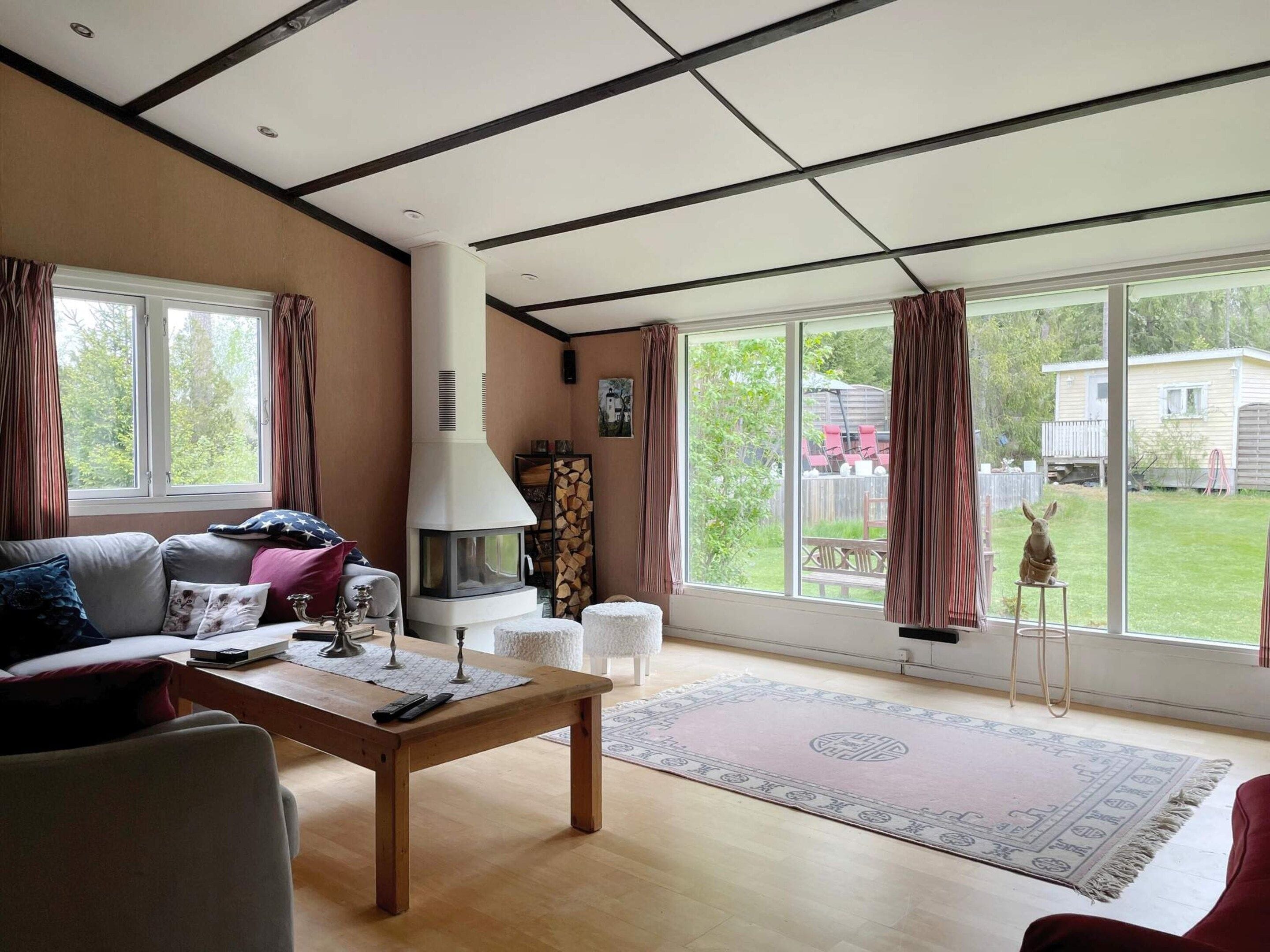 Una sala de estar con chimenea, un sofá, una mesa de centro y vista al patio trasero.