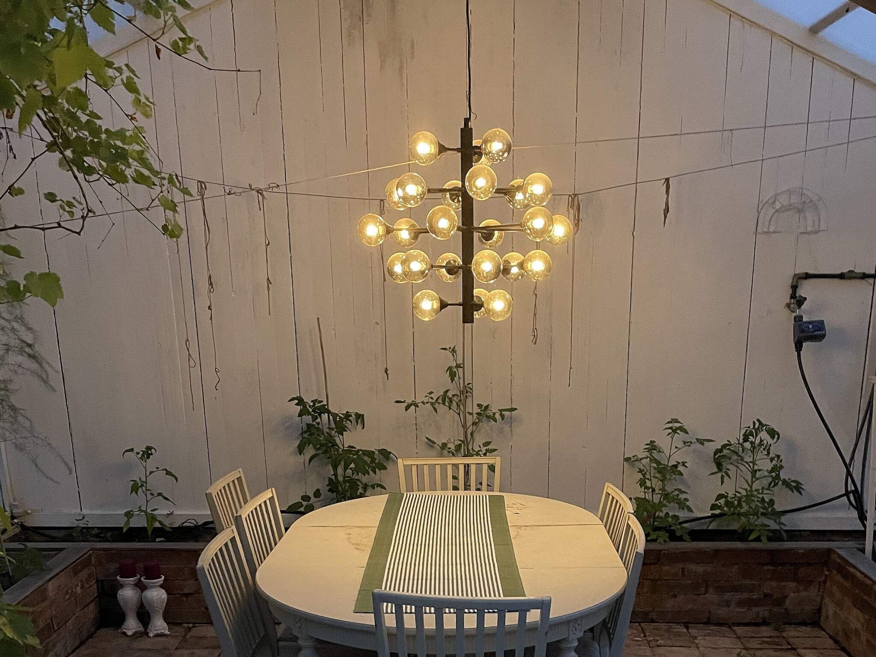 An outdoor dining area with a round table, chairs, and a hanging light fixture.