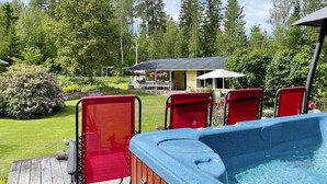 Ein Whirlpool mit vier roten Stühlen, einer Holzterrasse und einem Haus im Hintergrund.