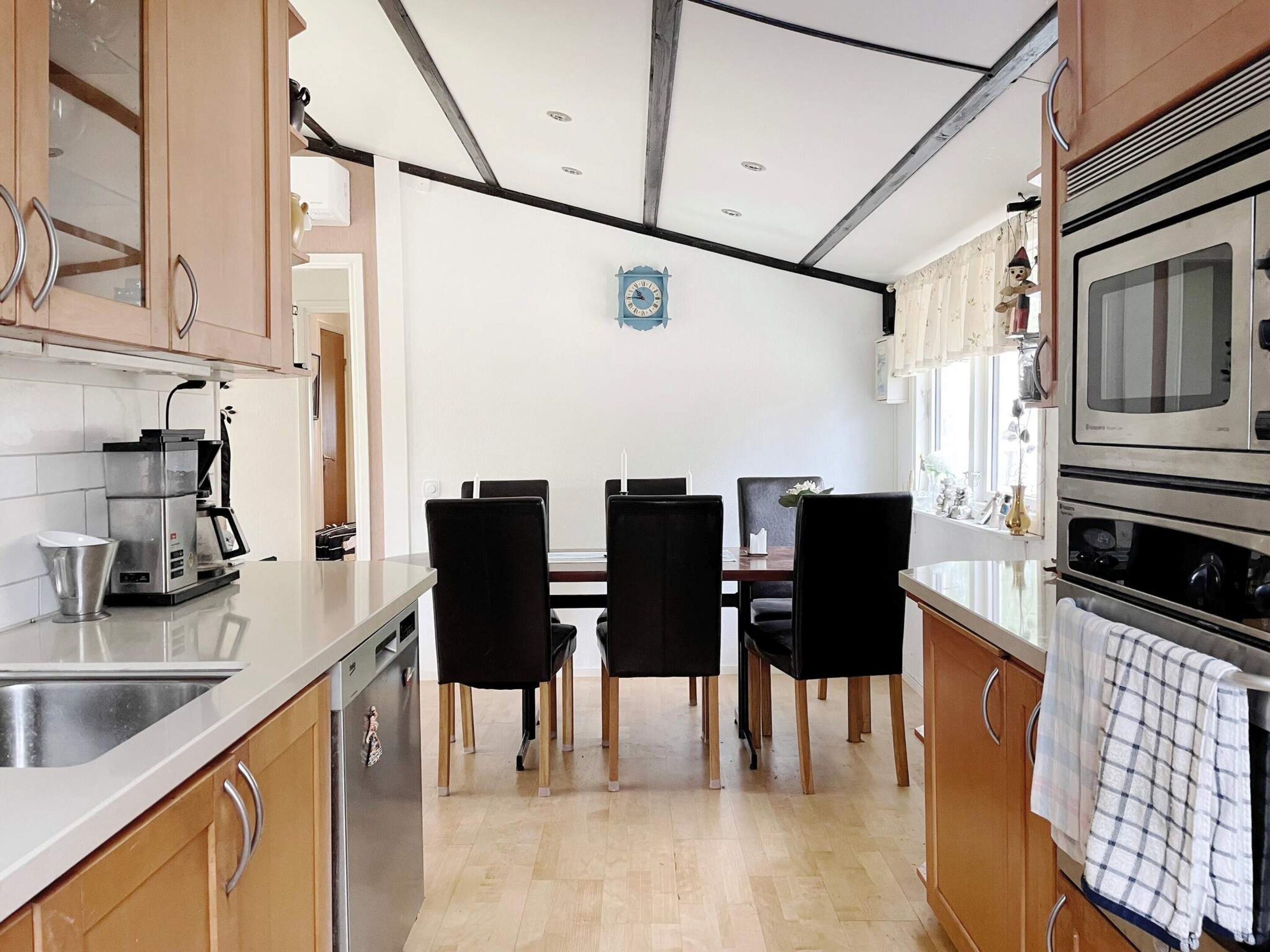 A kitchen with a dining table, chairs, a coffee machine, and a microwave.