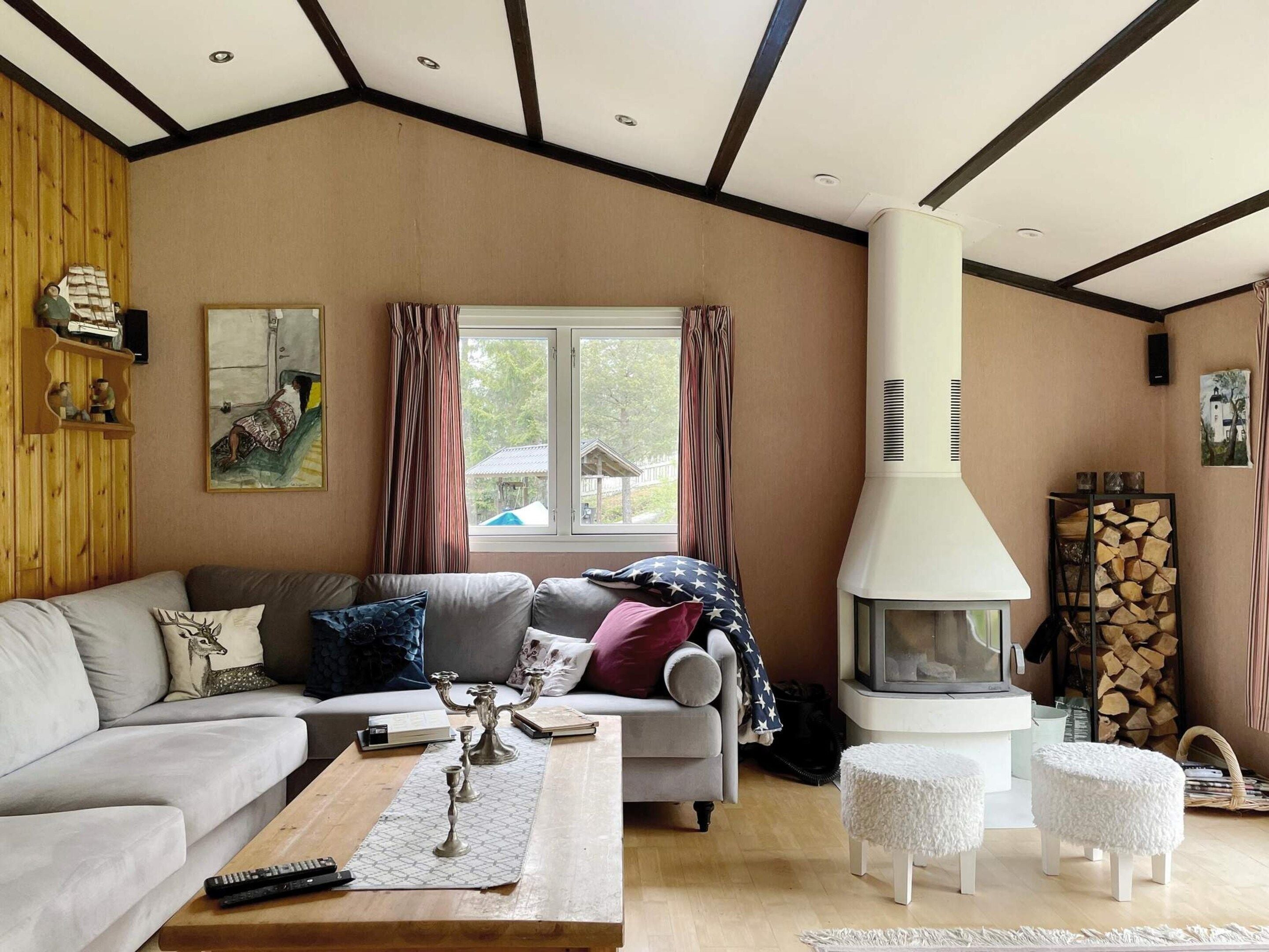 Una sala de estar con un sofá, una mesa de centro, una chimenea y un ventanal con cortinas.